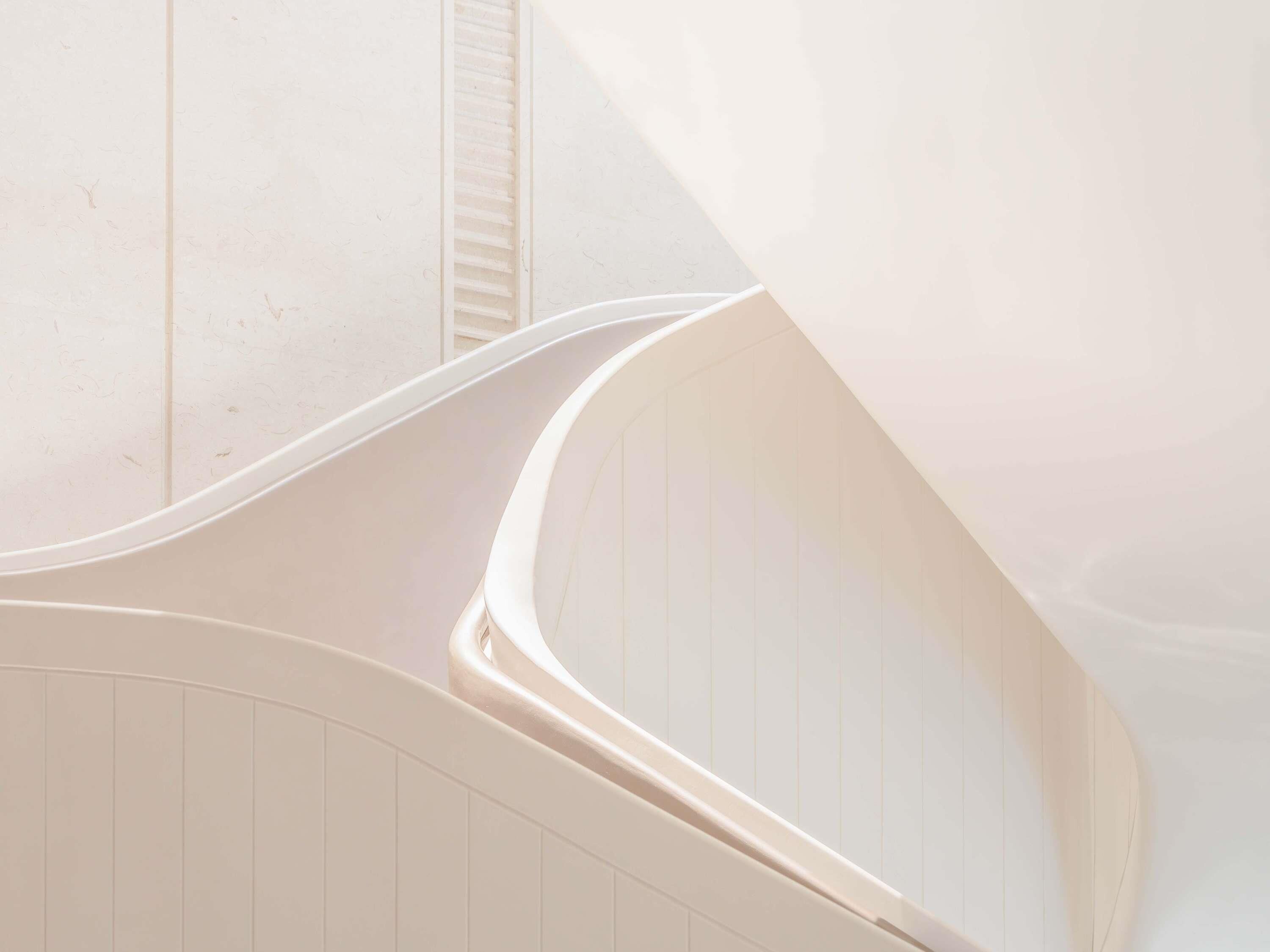Una escalera curva con barandilla blanca que conduce a un piso superior.
