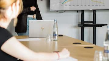 A conference room with a laptop, water bottle, and a presentation screen displaying a line graph.