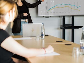 A conference room with a laptop, water bottle, and a presentation screen displaying a line graph. - Greet Hotel Brest Aéroport (Guipavas)
