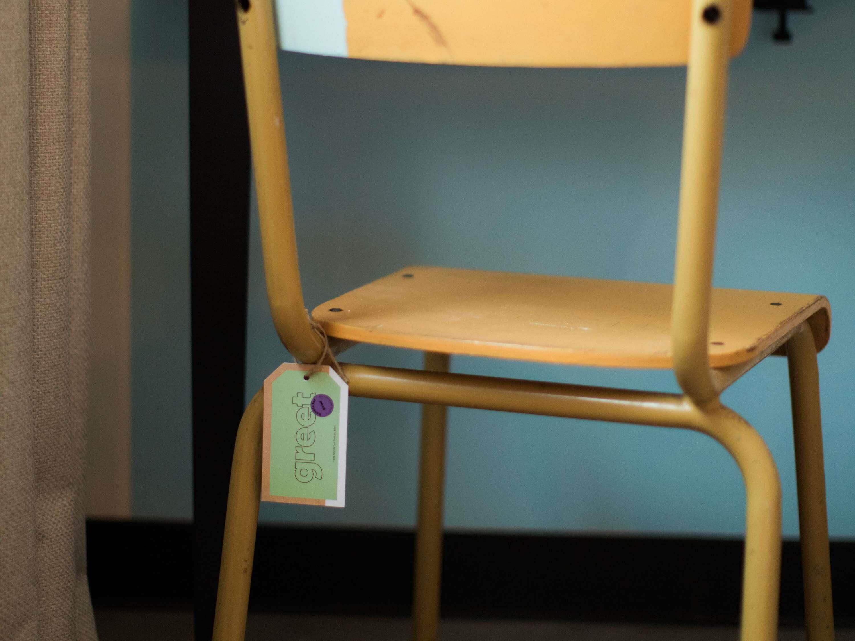 A chair with a tag attached to the backrest.