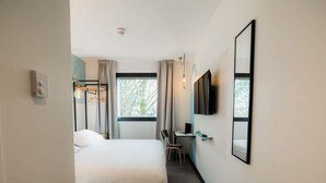 A hotel room with a bed, a desk, a chair, a TV, and a window. - Greet Hotel Brest Aéroport (Guipavas)