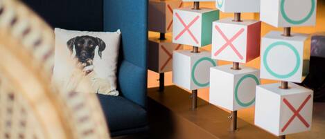 A modern hotel lobby with a blue sofa, a decorative pillow, and a wall of illuminated cubes.