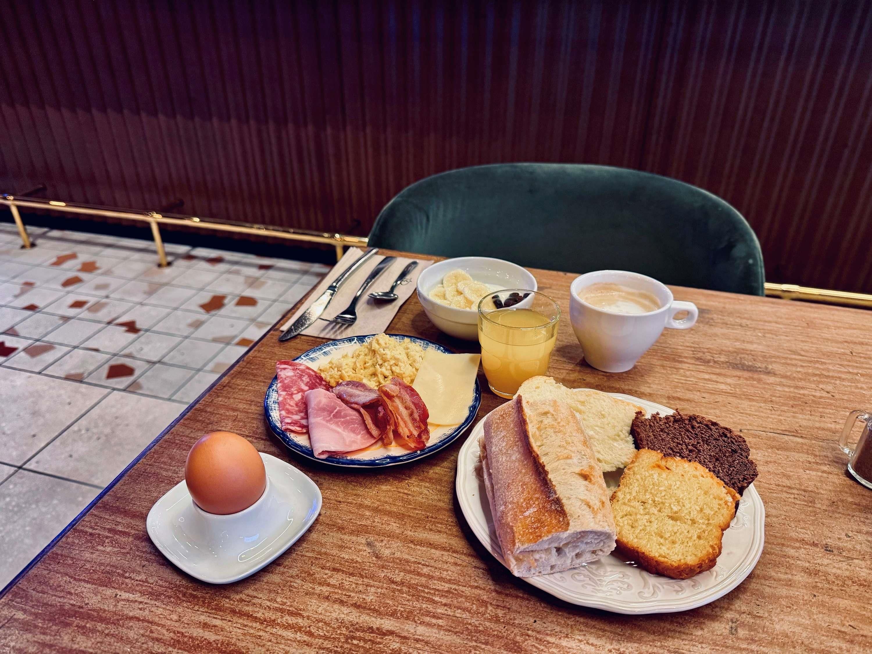 Una mesa de desayuno con platos de comida, una taza de café y un bol de fruta.