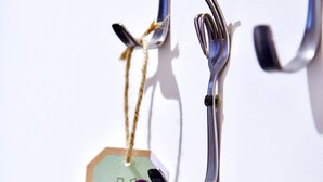 A metal hook with a tag attached, hanging against a white background. - Greet Hotel Brest Aéroport (Guipavas)