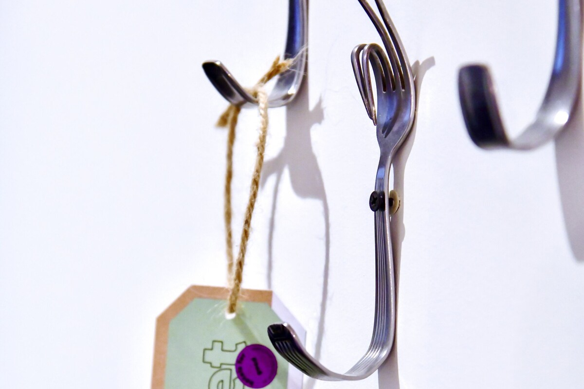 A metal hook with a tag attached, hanging against a white background.