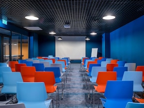 A conference room with rows of chairs, a projector screen, and a whiteboard. - ibis Styles Batumi  (Batumi)