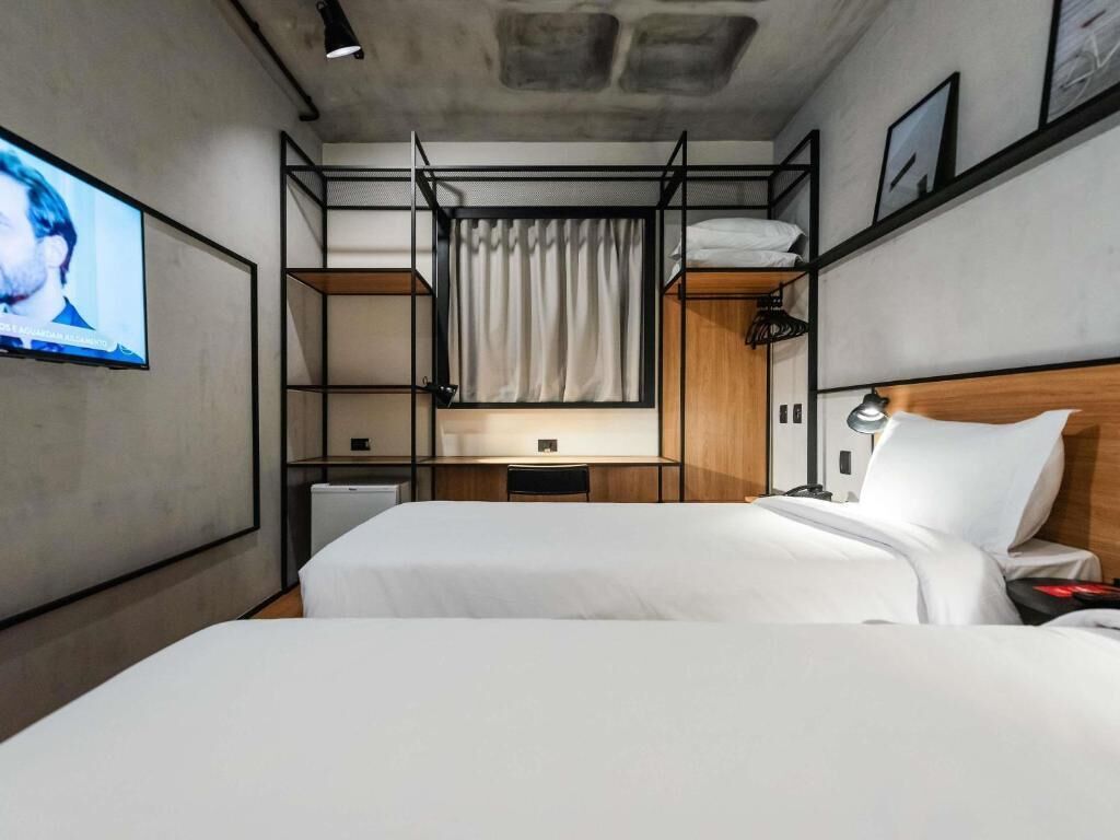 Une chambre d’hôtel avec des lits superposés, un bureau, une télévision et une lampe de chevet.