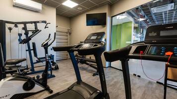 Et fitnessrum med træningsmaskiner, løbebånd og spinningcykel.