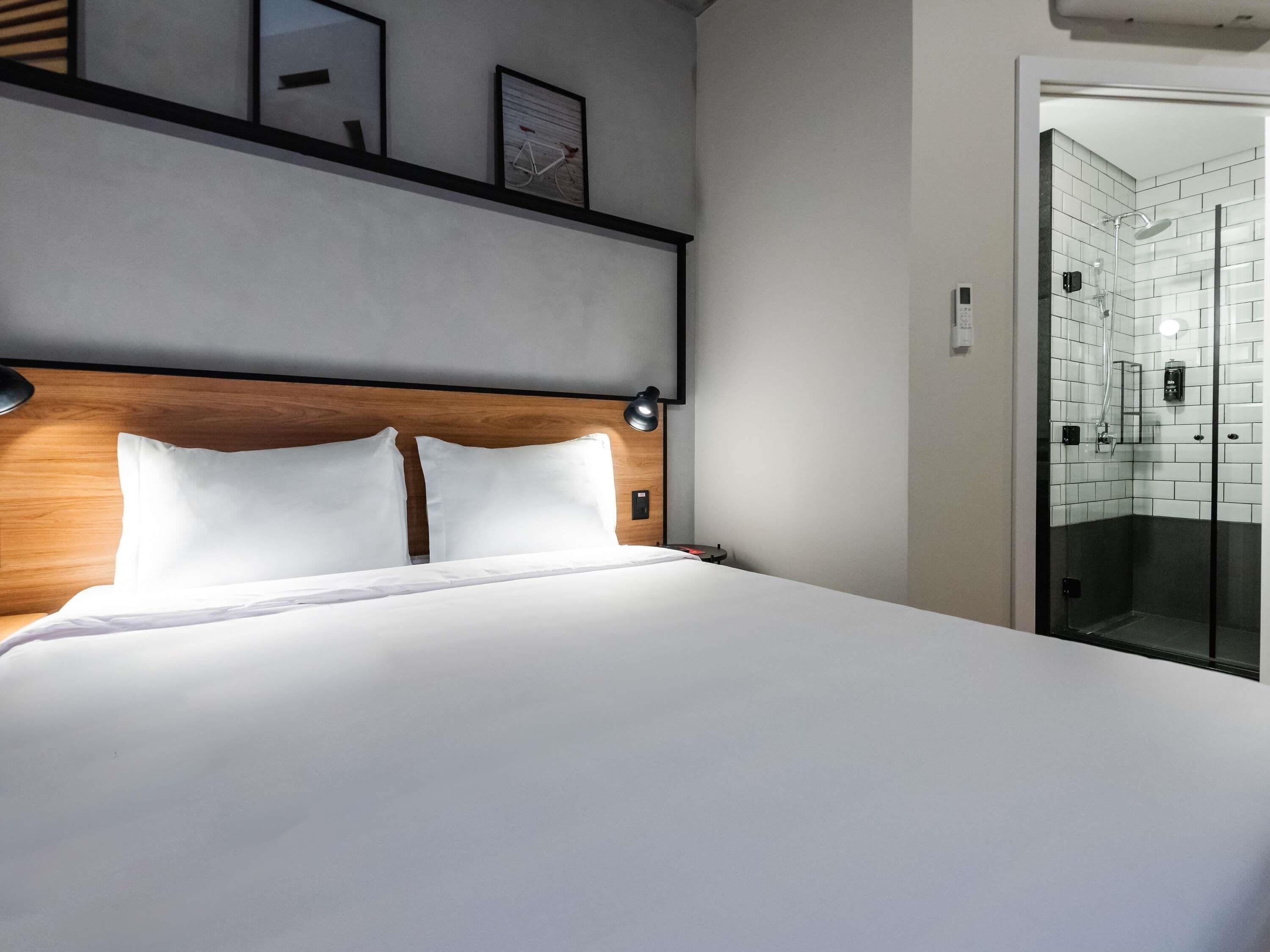 A neatly made bed with a wooden headboard, a bedside lamp, and a framed picture on the wall.