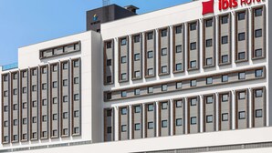 Un hôtel moderne à plusieurs étages, dont la façade est ornée d’une grande enseigne « Ibis Hotel ».