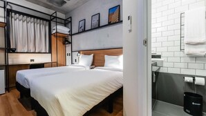 Une chambre d’hôtel moderne avec un grand lit, un petit bureau et une salle de bain équipée d’un porte-serviettes.