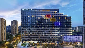 Un hotel moderno con un llamativo letrero de 'NOVOTEL', varios pisos y una fachada bien iluminada.