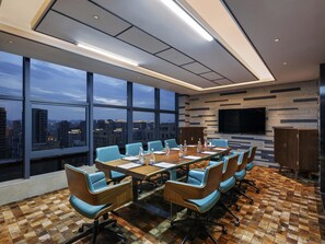 Une salle de conférence avec vue sur la ville, de grandes fenêtres, un téléviseur à écran plat et un sol à carreaux.
