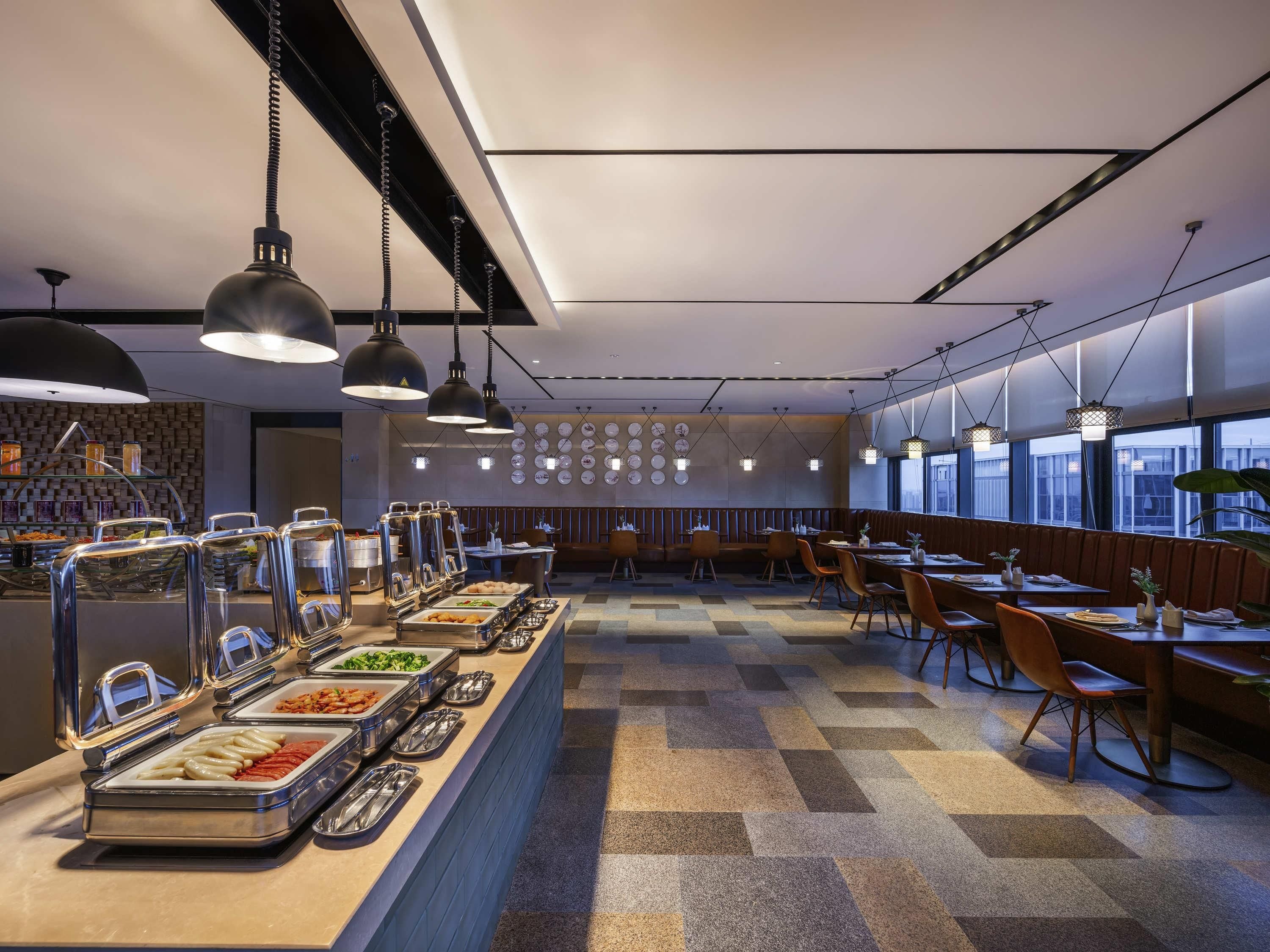 Uma área de refeições moderna com balcões de buffet, arranjos de assentos e uma parede decorada com pratos.