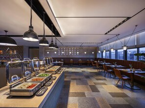 Un espace repas moderne doté de comptoirs de buffet, d’un aménagement pour s’asseoir et d’un mur décoré d’assiettes.