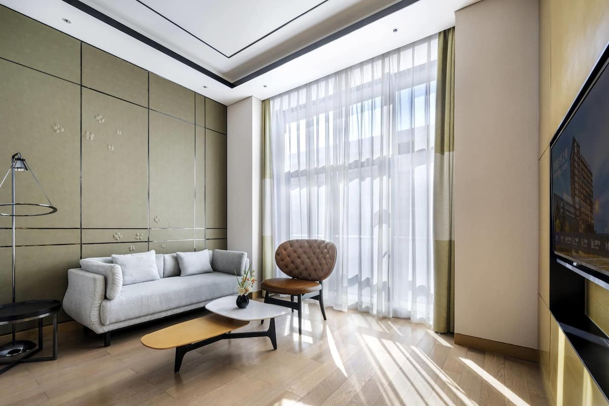 Una sala de estar moderna con un sofá, un sillón, una mesa de centro y un televisor en la pared.