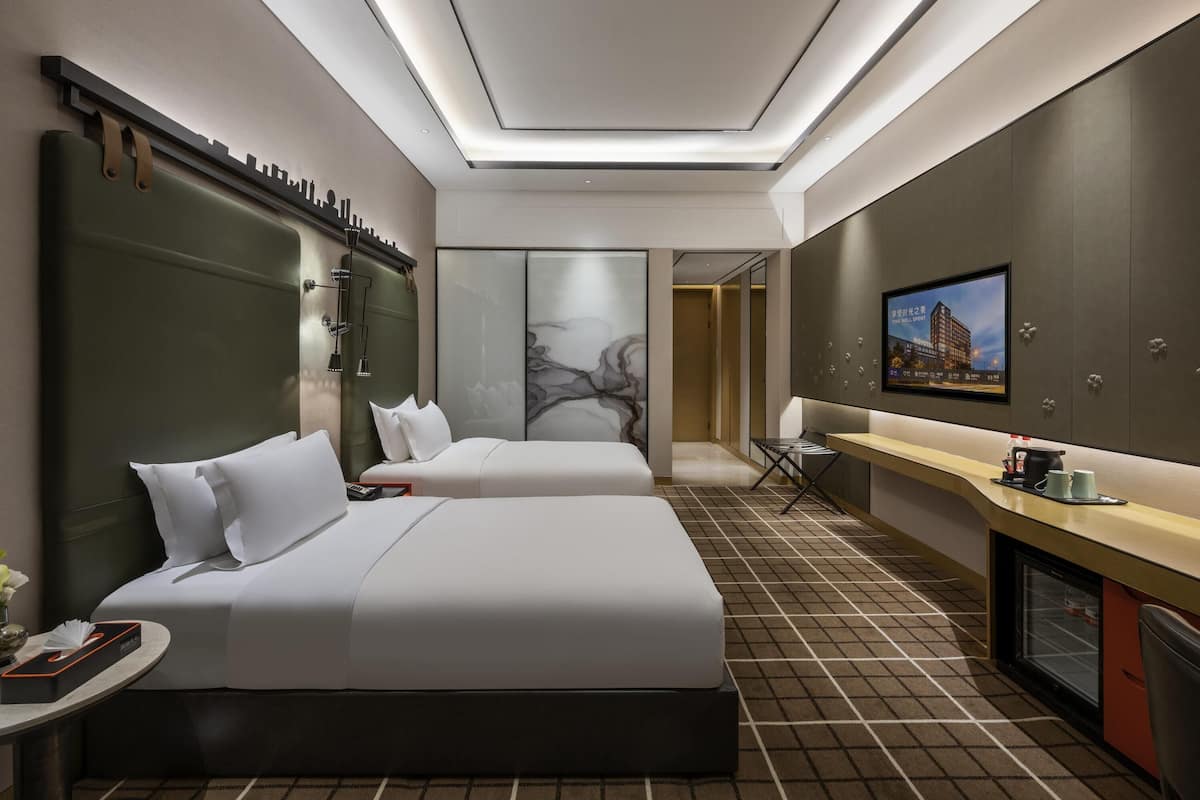 Una habitación de hotel con dos camas, un escritorio, un televisor y un minibar.