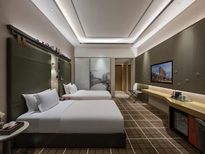 A hotel room with two beds, a desk, a TV, and a minibar.