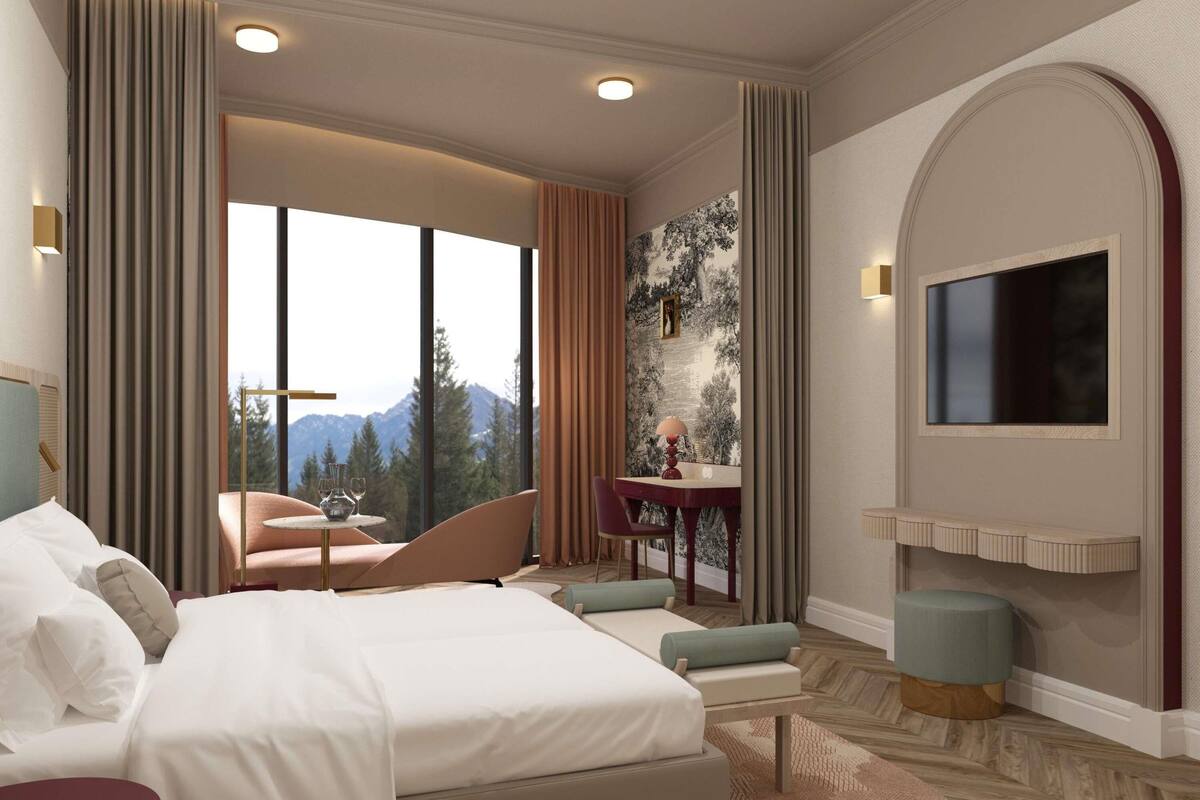 Ein Hotelzimmer mit einem großen Bett, einer Sitzecke mit Tisch, einem an der Wand montierten Fernseher und Bergblick durch das Fenster.