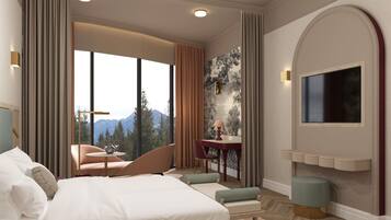 A hotel room with a large bed, a seating area with a table, a TV mounted on the wall, and a view of mountains through the window.
