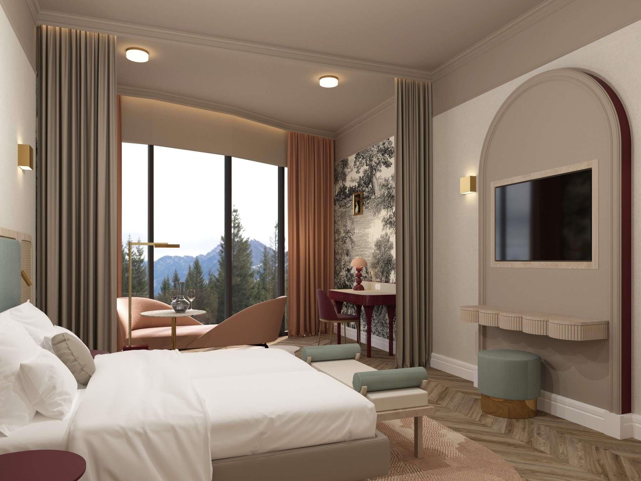 A hotel room with a large bed, a seating area with a table, a TV mounted on the wall, and a view of mountains through the window.