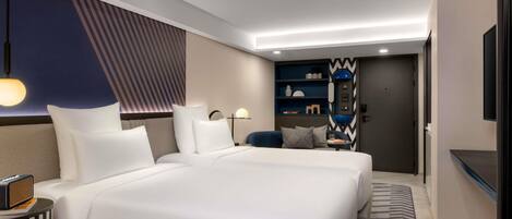 A modern hotel room with a large bed, bedside tables, a desk, and a television.