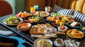 A breakfast table with various dishes, including toast, eggs, and fruit.