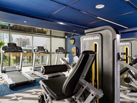 Un gimnasio con cintas de correr, máquinas de pesas y un espejo grande.