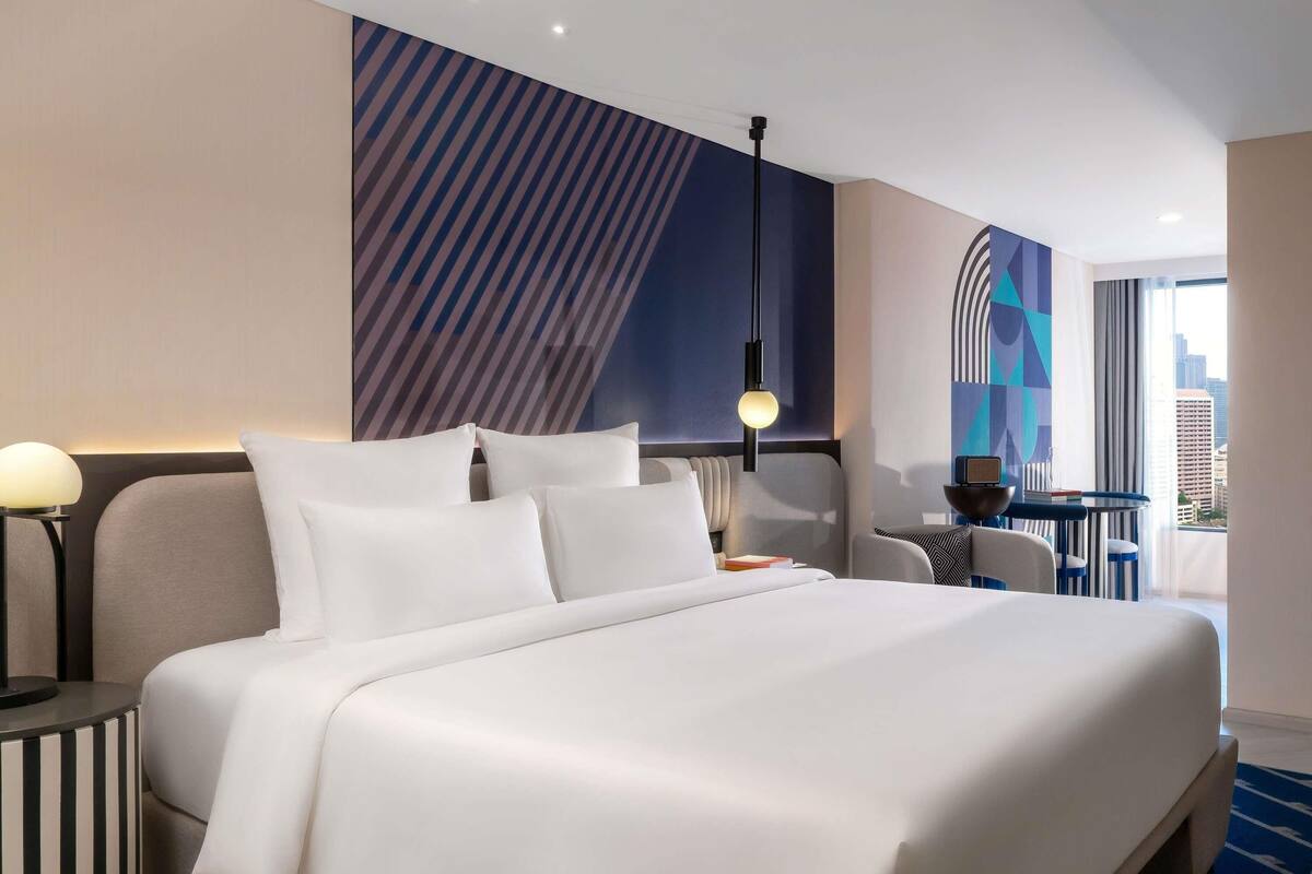 Una habitación de hotel moderna con una cama grande, un escritorio y vistas a la ciudad.