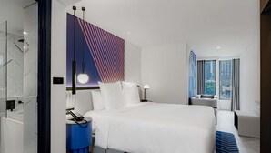 A modern hotel room with a large bed, a desk, and a view of the city through the window. - TRIBE Living Bangkok Sukhumvit 39 by AccorHotels (Bangkok)