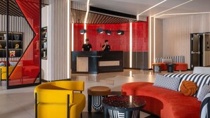 A modern hotel lobby with a reception desk, seating area, and a staircase. - TRIBE Living Bangkok Sukhumvit 39 by AccorHotels (Bangkok)