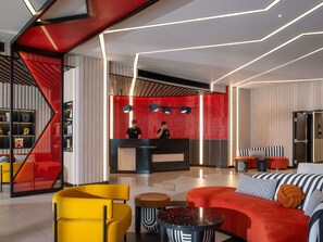 En modern hotellobby med en receptionsdisk, en sittgrupp och en trappa.