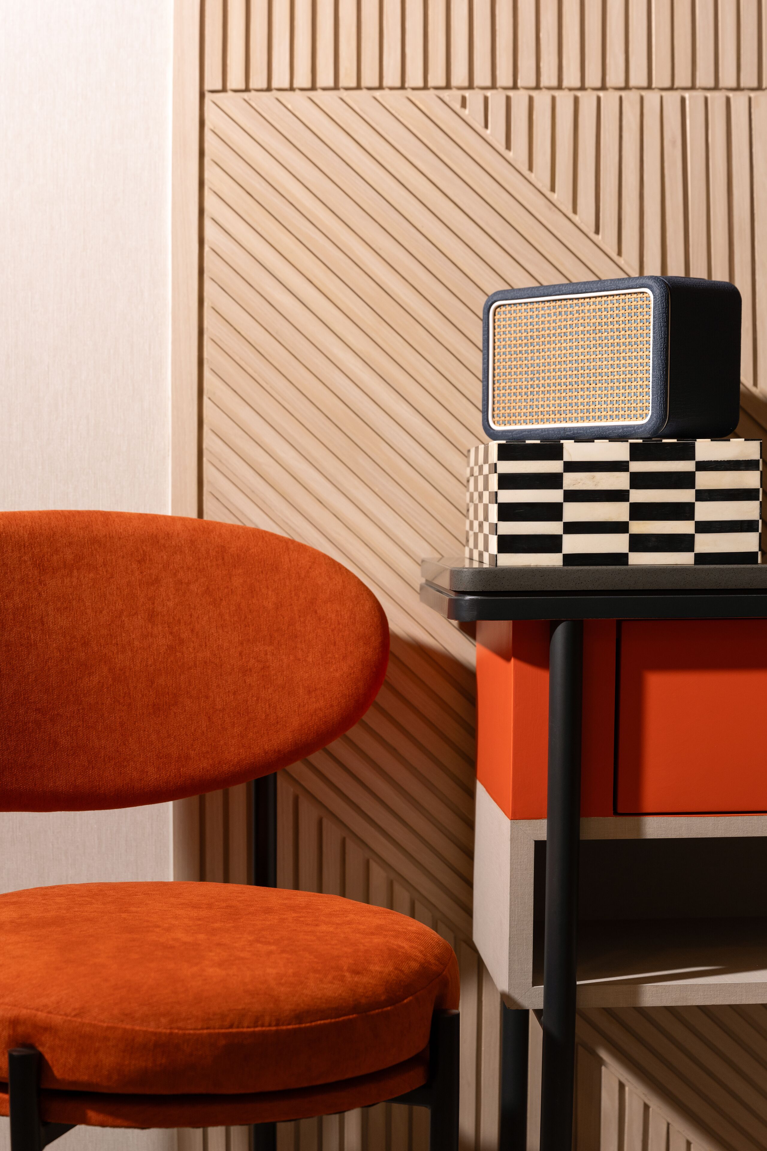 Une chaise avec un coussin à carreaux et une table avec une radio.