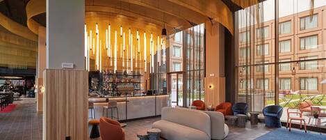 A modern lobby with a bar area, seating, and large windows.