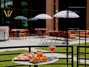 An outdoor dining area with tables, chairs, and umbrellas. - Tribe Milano Malpensa (Vizzola Ticino)