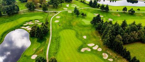 Un campo de golf con búnkeres de arena, obstáculos acuáticos y un estanque.