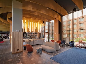 A modern lobby with a bar area, seating, and large windows.
