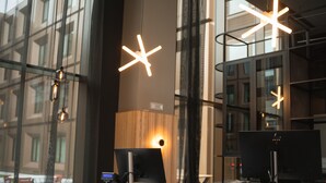 Un espacio de oficina moderno con ventanas amplias, luminarias contemporáneas y monitores de computadora.