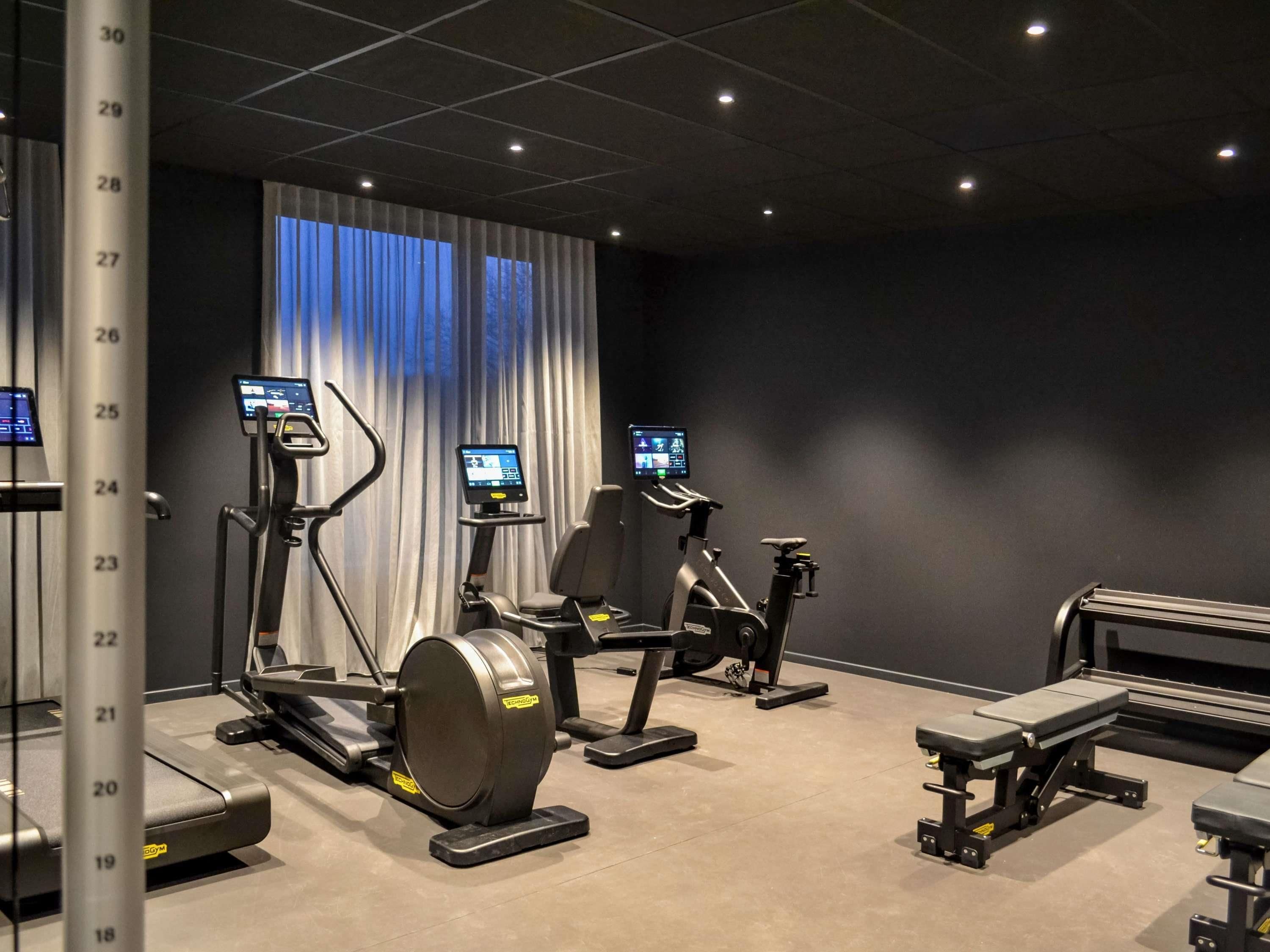 Uma academia com esteiras, bicicletas ergométricas e máquinas de musculação.