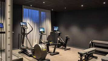 Uma academia com esteiras, bicicletas ergométricas e máquinas de musculação.