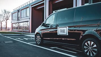 Una camioneta negra estacionada frente a un edificio moderno con ventanas grandes y un balcón.
