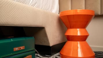 A room with a bed, a patterned wall, a green suitcase, and an orange object.