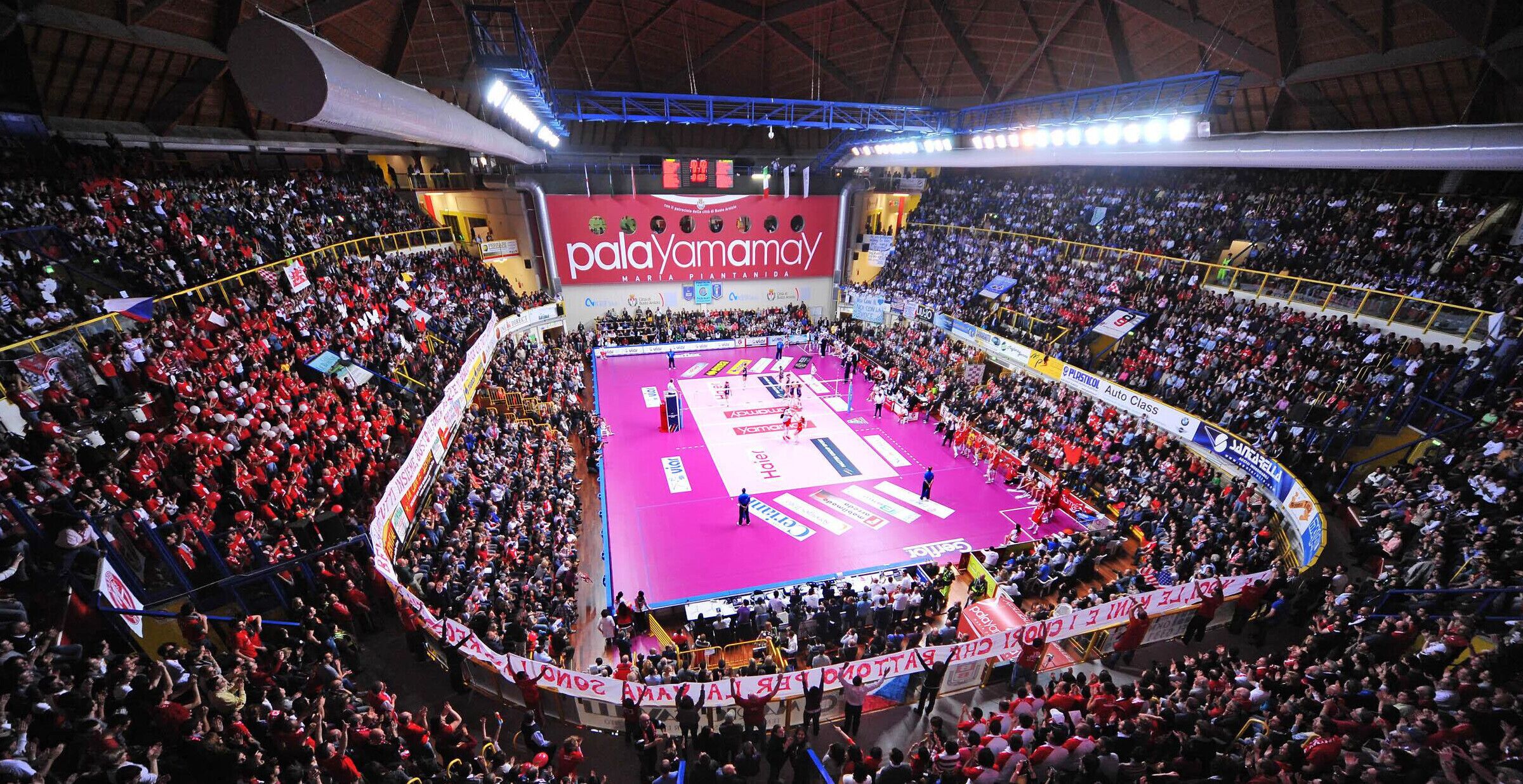 Una gran arena cubierta para deportes, con una cancha central rodeada de gradas para espectadores.