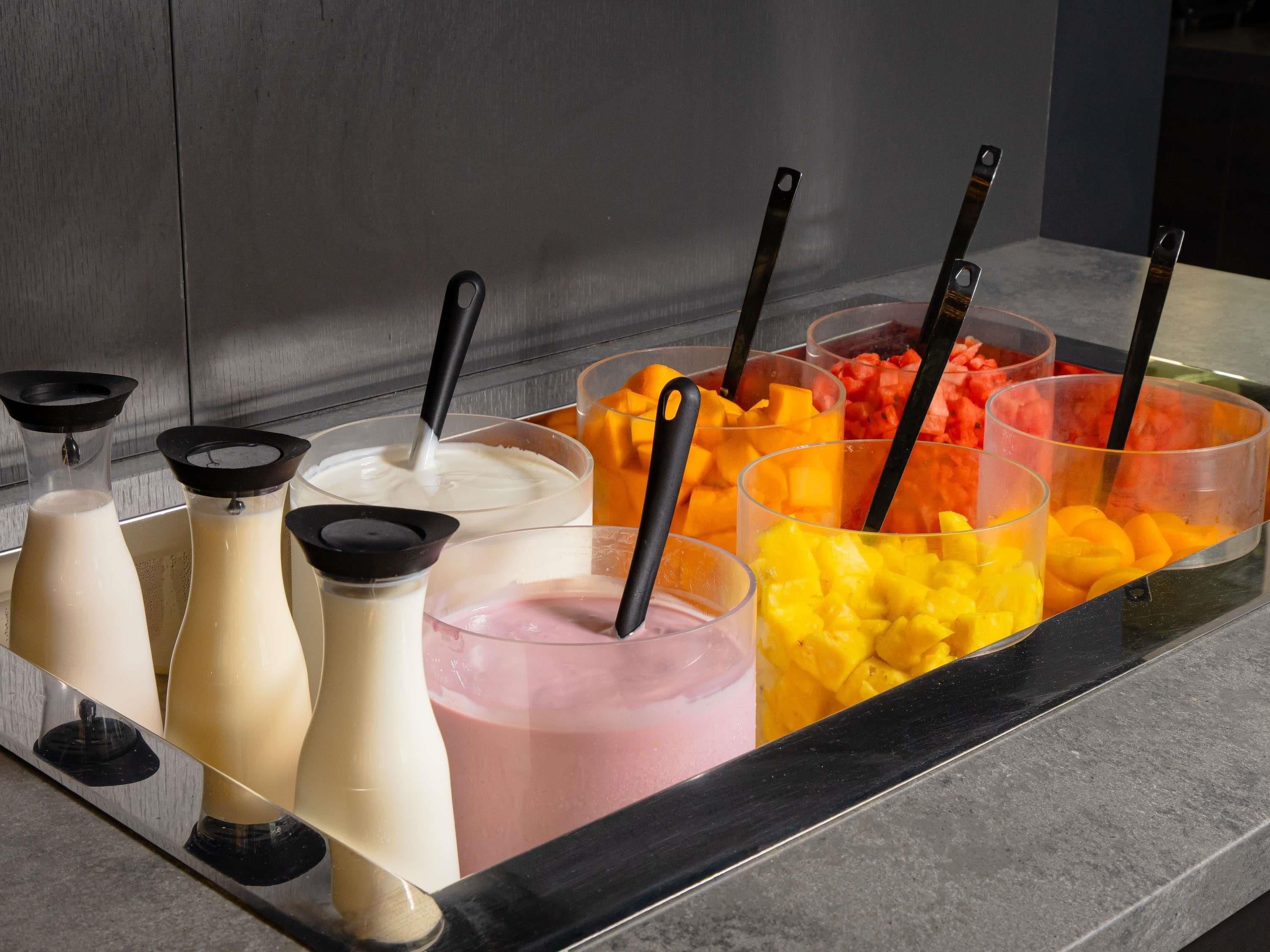 A self-serve beverage station with various drinks and fresh fruits.