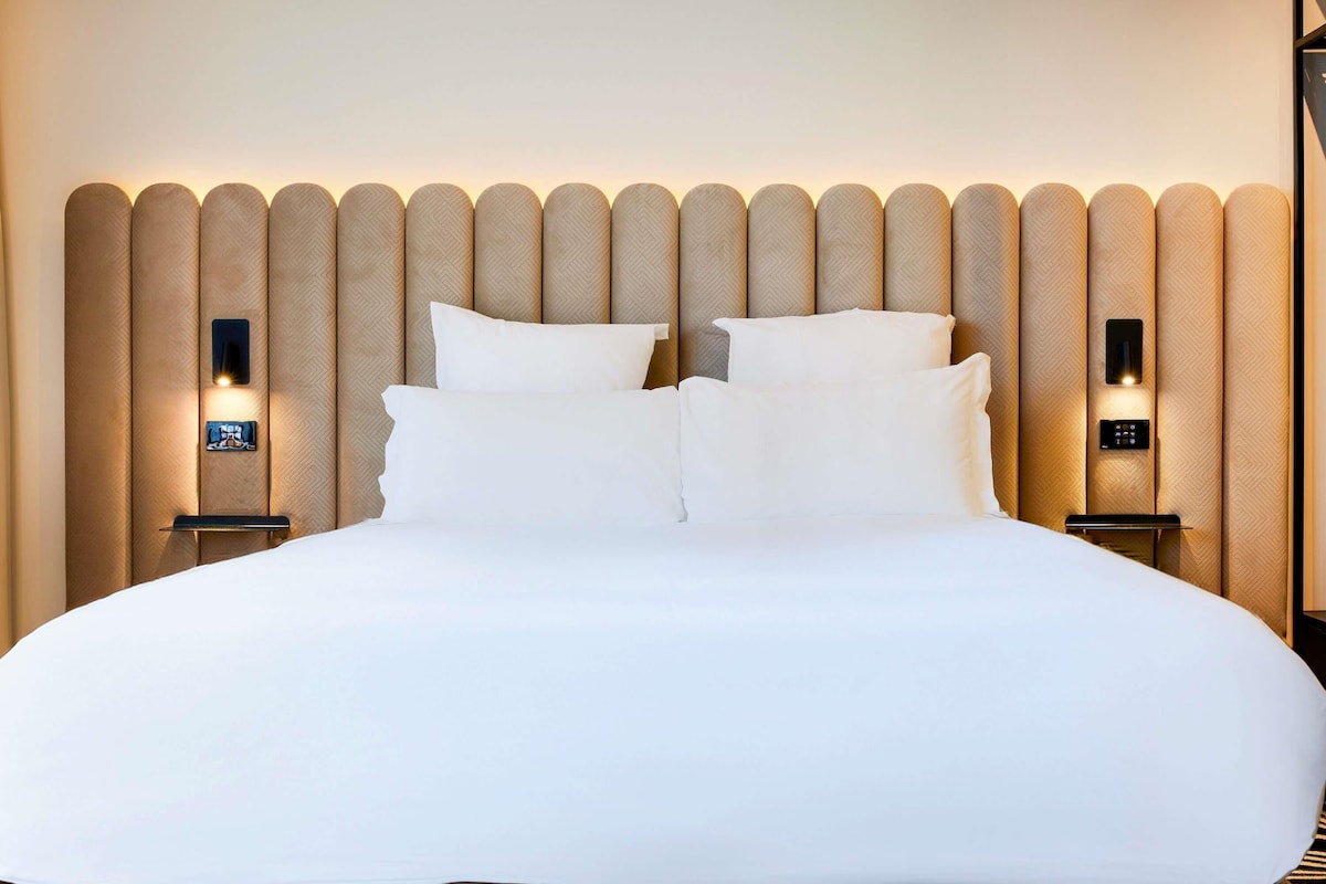 A neatly made bed with a headboard featuring vertical panels and integrated lighting.