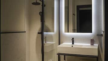 A modern bathroom with a glass shower enclosure, a white sink, a mirror, and a towel rack.