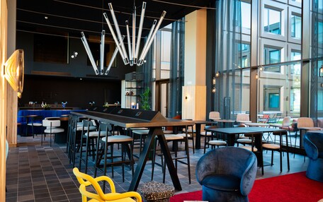A modern lounge area with a bar, seating arrangements, and a contemporary light fixture.