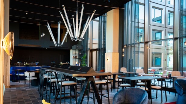 Un área de lounge moderna con barra, diferentes disposiciones de asientos y una lámpara contemporánea.
