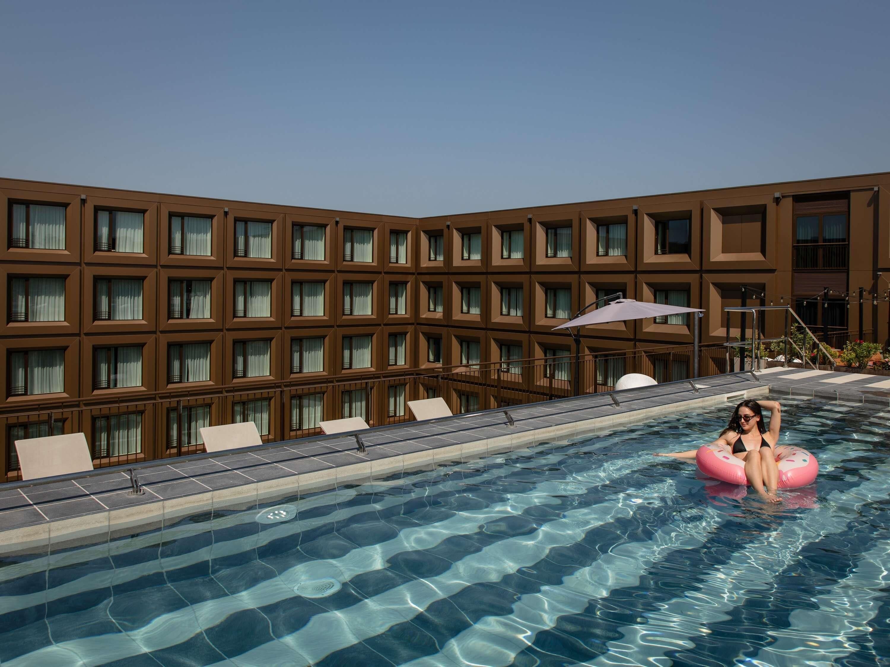 A swimming pool with clear water, surrounded by a modern building with multiple windows.