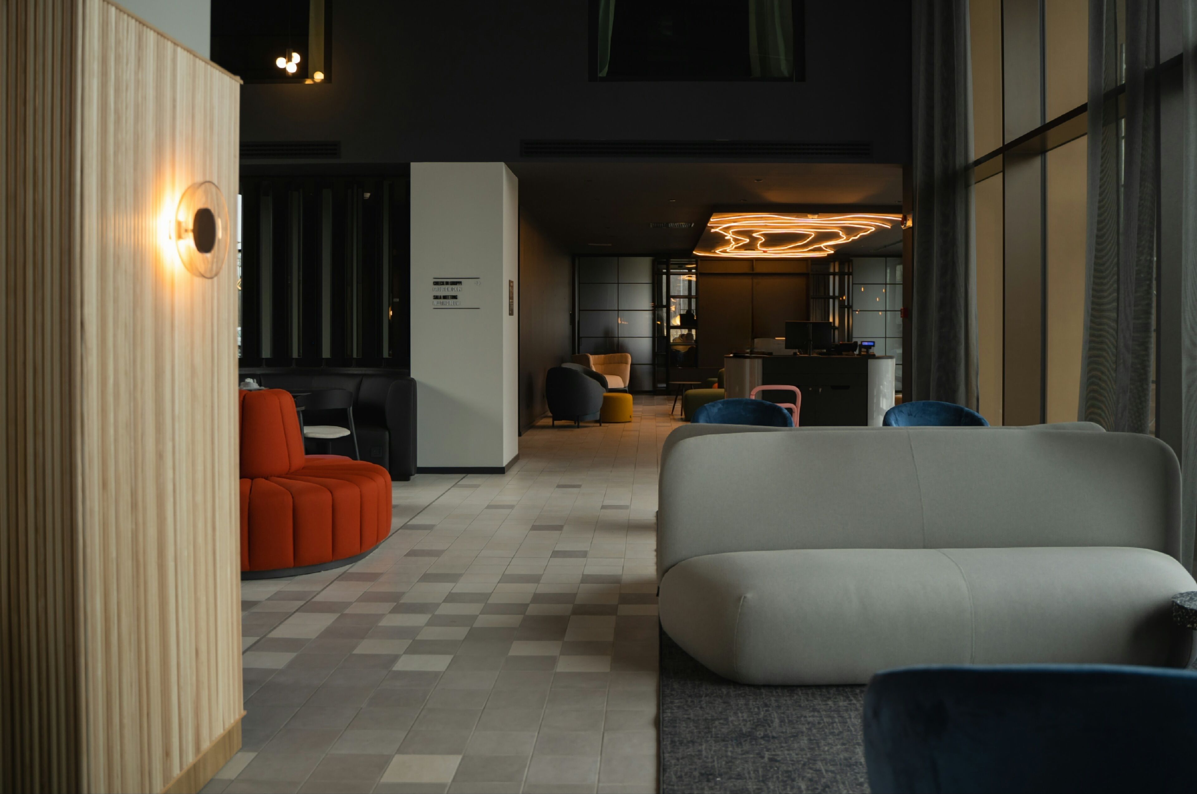 Un hall d’entrée moderne avec un sol à carreaux, un canapé blanc et un fauteuil rouge.